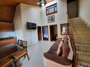 ein Wohnzimmer mit einem Sofa, einem TV und einer Treppe in der Unterkunft Hotel El Lago in Paipa