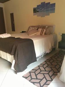 a bedroom with a large bed and a rug at BLUE DOOR BRASIL in Abraão