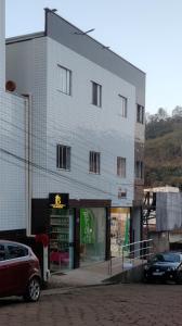 a large gray building with cars parked in front of it at kitnet Ragnarok in Barão de Cocais