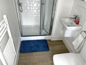 uma casa de banho com um chuveiro, um lavatório e um tapete azul em Luxury Northampton Town Centre Apartment em Northampton