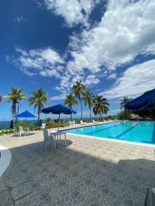 una piscina con palmeras y sombrillas azules en Apartamento con playa privada en Santa Marta, en Santa Marta
