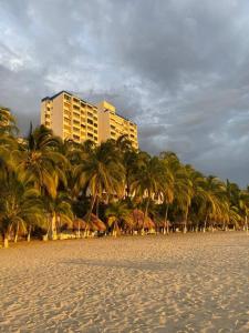 un grupo de palmeras en una playa con un edificio en Apartamento con playa privada en Santa Marta, en Santa Marta