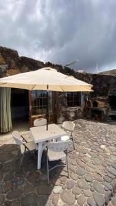 Aprtamento Rural, vistas al mar El Hierro في El Pinar del Hierro: طاولة وكراسي مع مظلة على الفناء