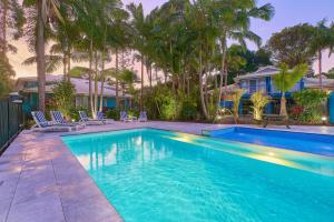 una piscina en un patio con palmeras en Flynns on Surf Beach Villas, en Port Macquarie