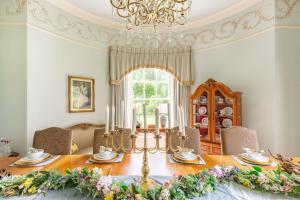 a dining room with a table and a chandelier at Luxury Scottish Manor house + jacuzzi + bbq cabin + helipad in Maybole