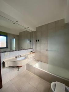 Un baño con bañera, lavabo y espejo. en Hotel Las Chirimoyas, en Salta