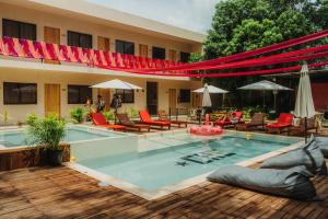 a swimming pool with chairs and umbrellas next to a building at Che Valladolid Hostel & Bar in Valladolid