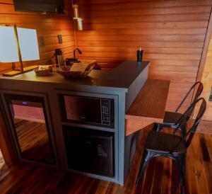 a kitchen with a microwave and a table and chair at Vinícola D'alture - Cabana Casal - Sangiovese in São Joaquim