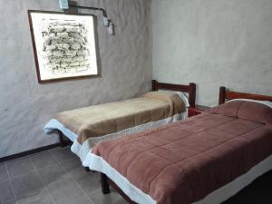 2 camas en una habitación con una foto en la pared en Posada Casablanca en La Carolina