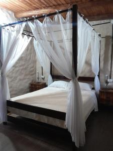 1 dormitorio con cama con dosel y cortinas blancas en Posada Casablanca en La Carolina