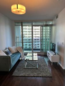 een woonkamer met een bank en een glazen tafel bij Lakeview Condo in Downtown with Free Parking. in Toronto