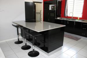 a kitchen with black cabinets and a white tile floor at Villa Rubis - proche aéroport in Matoury