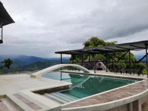 a swimming pool with a bridge and mountains in the background at FINCA LA FORTALEZA in Santa Rosa de Cabal