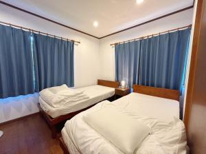 函南町にあるフォレストハウス伊豆箱根の青いカーテンが備わる客室のベッド2台