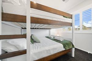 a bedroom with bunk beds and a window at The Seachange - Brand New, Beachy Family Retreat. in Ettalong Beach