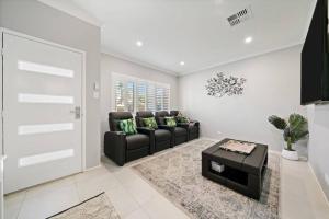 a living room with a black couch and a table at The Seachange - Brand New, Beachy Family Retreat. in Ettalong Beach