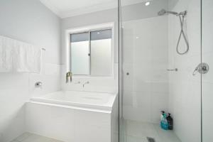 a white bathroom with a tub and a shower at The Seachange - Brand New, Beachy Family Retreat. in Ettalong Beach +22 photos