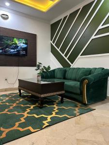 a living room with a green couch and a coffee table at Balcony View/Aesthetic One bedroom Apartment in Islamabad