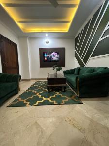 a living room with two green couches and a tv at Balcony View/Aesthetic One bedroom Apartment in Islamabad