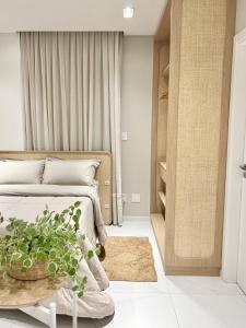 a bedroom with a bed and a potted plant at Loft Boho - Cosmopolitan - Oktoberfest in Blumenau