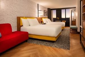 two beds in a hotel room with a red couch at Pleasant Unit at New York New York Strip Las Vegas in Las Vegas