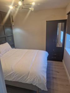Schlafzimmer mit einem weißen Bett und einem Spiegel in der Unterkunft Collier's Wood en-suite apartments in London