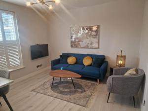 a living room with a blue couch and a chair at Collier's Wood en-suite apartments in London