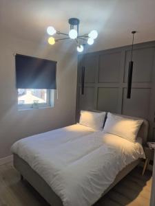 a bedroom with a large white bed with a ceiling fan at Collier's Wood en-suite apartments in London