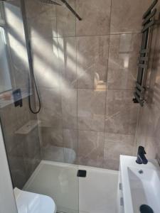 ein Bad mit einer Dusche, einem WC und einem Waschbecken in der Unterkunft Collier's Wood en-suite apartments in London