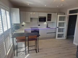 eine Küche mit weißen Schränken und einer schwarzen Arbeitsplatte in der Unterkunft Collier's Wood en-suite apartments in London