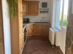 kuchnia z drewnianymi szafkami, umywalką i oknem w obiekcie Charming Ardennes house with jacuzzi for 8 people w mieście Noiseux