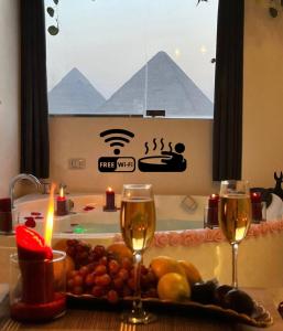 a table with two glasses of wine and a plate of fruit at Pharaoh pyramids room in Cairo +10 photos