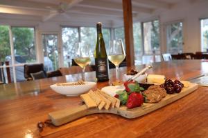 a table with a plate of food and a bottle of wine at Whispering Gums - Ocean Views, Pet Friendly, EV UNIT 7kW for electric cars, Sleeps 7 in Lorne