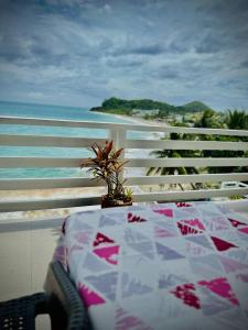 a table with a plant on a balcony with the ocean at Playa Blanca Beach Resort in Puerto Galera