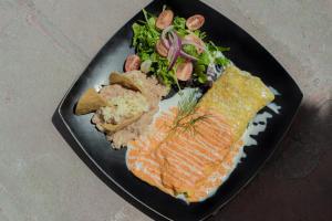 um prato preto de alimentos com arroz de peixe e legumes em Atotonilco Hotel & Club em Atotonilco
