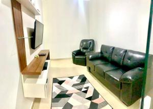 uma sala de estar com um sofá de couro preto e uma televisão em Recanto Algodão-Doce - Área de Lazer em São Carlos em São Carlos