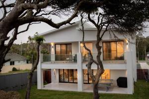 uma grande casa branca com uma árvore em primeiro plano em Sea & Sun Beach House em Norah