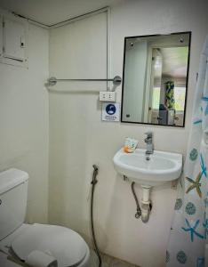 a bathroom with a toilet and a sink and a mirror at Playa Blanca Beach Resort in Puerto Galera
