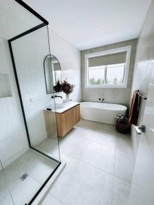 La salle de bains est pourvue d'une baignoire, d'un lavabo et d'un miroir. dans l'établissement Farm Stay in stunning new home, 
