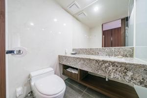 ein Badezimmer mit einem WC, einem Waschbecken und einem Spiegel in der Unterkunft Hotel Air City Jeju in Jeju-do