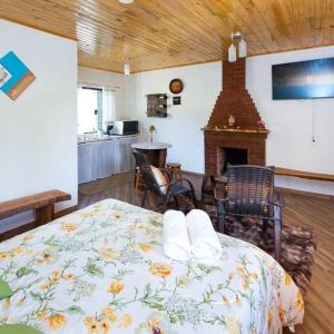 um quarto com uma cama e uma lareira num quarto em Chalé Lírio Cachoeira do Vale em Monte Verde