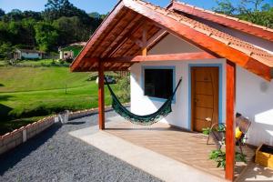 una casa con una hamaca fuera de ella en Chalé Lírio Cachoeira do Vale, en Monte Verde