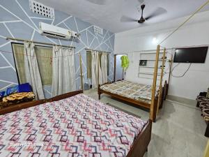 una camera da letto con due letti e una TV a schermo piatto di Sudha Kutir Puri a Puri