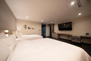 a bedroom with a large white bed and a flat screen tv at Hotel SUMMIT in Gwangju