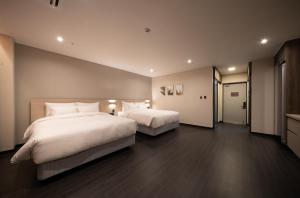 um quarto com 2 camas e almofadas brancas em Hotel SUMMIT em Gwangju