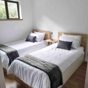 two beds in a white room with a window at Modern mountainside home with ocean view - Minimal load shedding in Cape Town