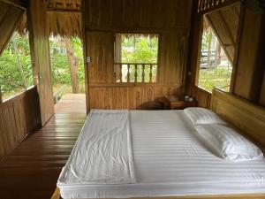a large bed in a wooden room with windows at Cuc Phuong Bungalow in Phủ Nho Quan