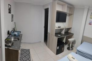 a small room with a bed and a desk with a television at Hotel Pousada Sol Nascente in Mafra