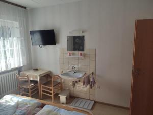 a bathroom with a sink and a table and a tv at Ferienhaus Seifert in Bischofsheim an der Rhön