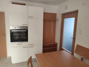 a kitchen with white cabinets and a table and a refrigerator at Ferienhaus Seifert in Bischofsheim an der Rhön